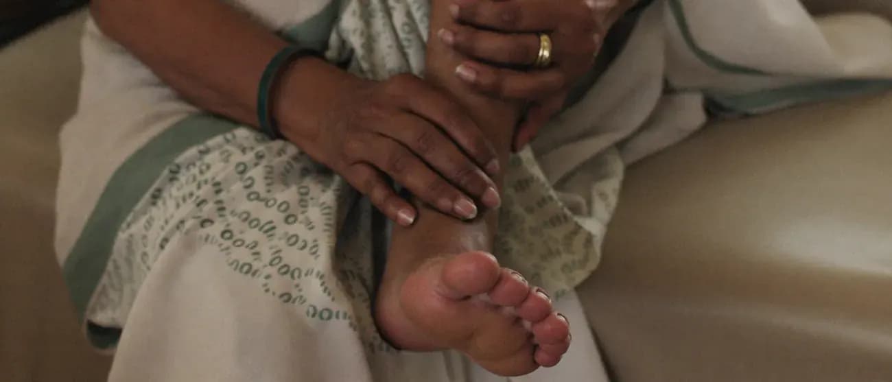 An older woman holding the aching arch and heel of her foot