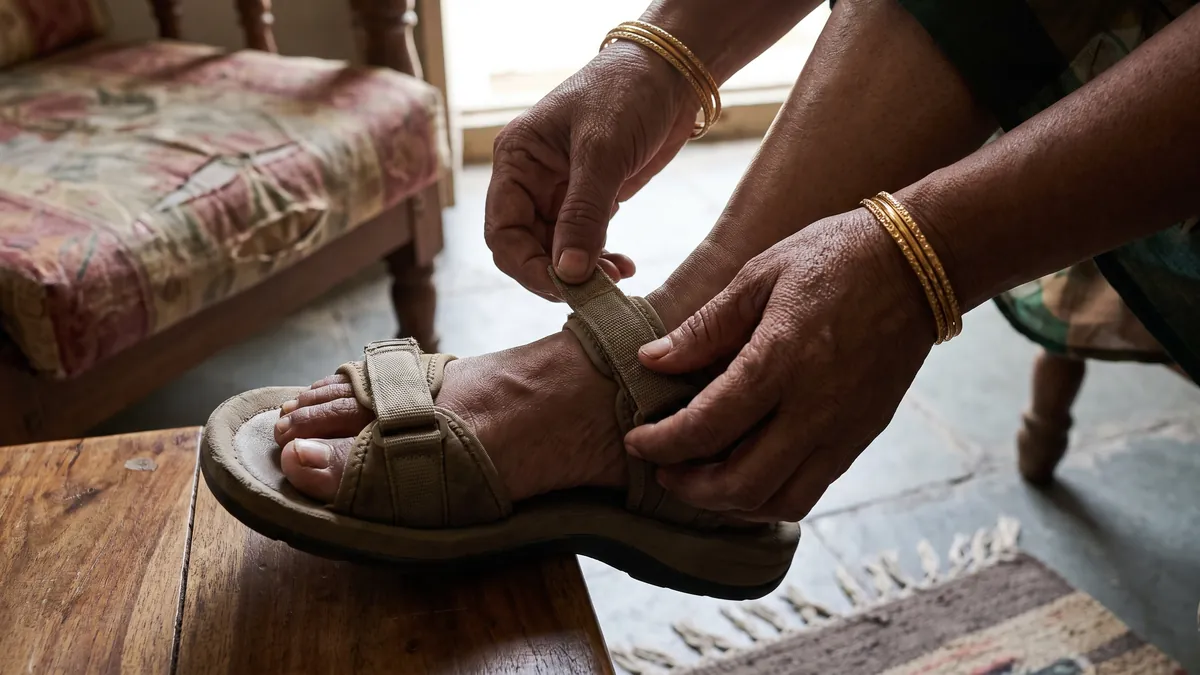 Woman adjusting the velcro strap of a cushioned sandal over a high instep