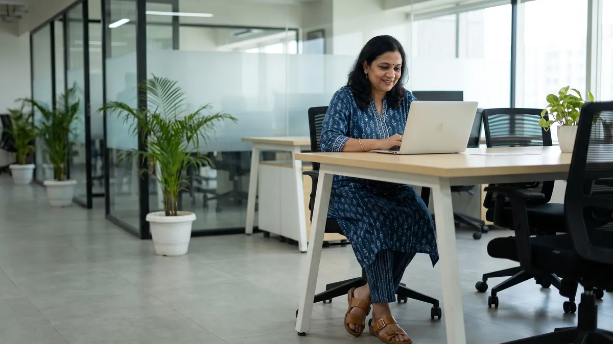 Working woman at an office desk wearing comfortable tan buckle-strap flat sandals