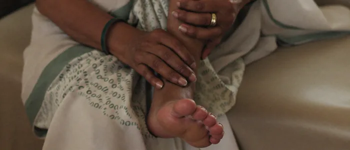 An older woman holding the aching arch and heel of her foot