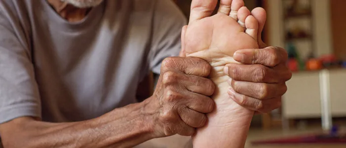 An older man pressing his thumbs into the painful arch of his foot