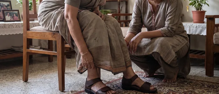 An older woman in AJL Diana orthopedic sandals with a family member helping check her feet